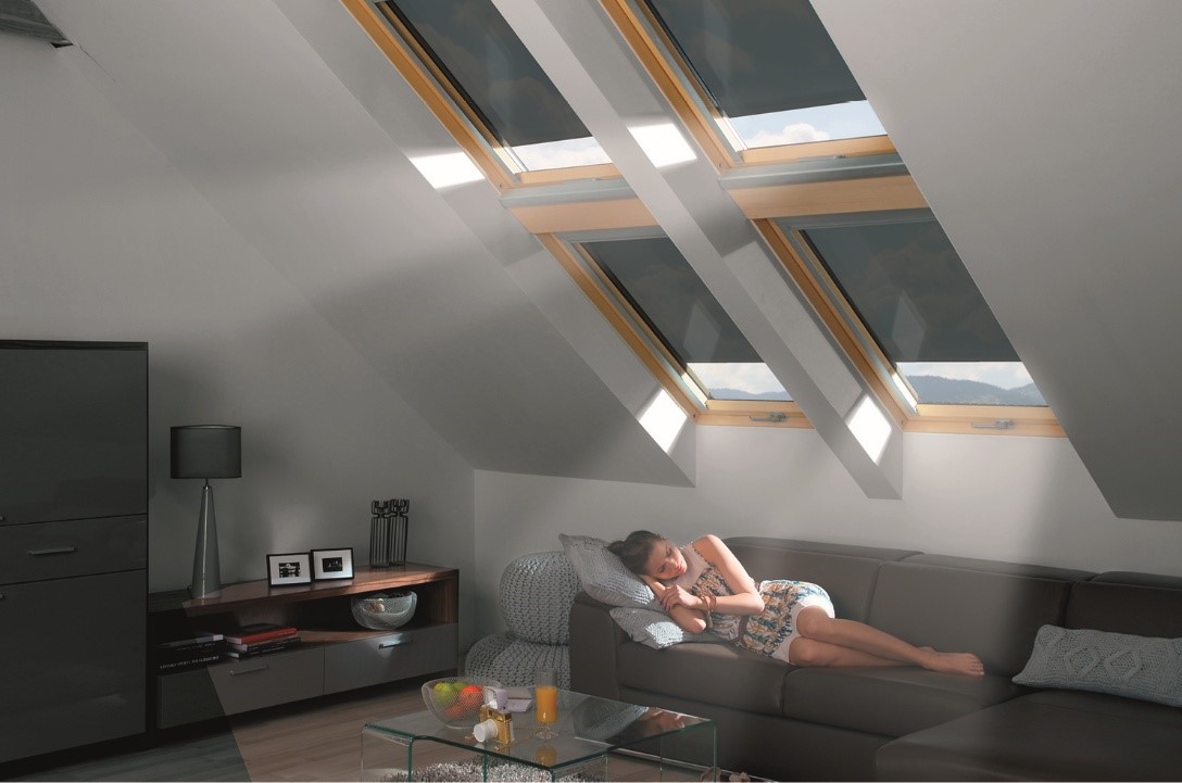 Frau entspannt sich auf einem Sofa unter Dachfenstern mit verdunkelnden Innenrollos.